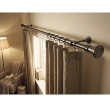 Vorhangstange aus Metall mit Ringen und Stoffvorhängen in einem hellen Raum mit Fenster und Sessel.
