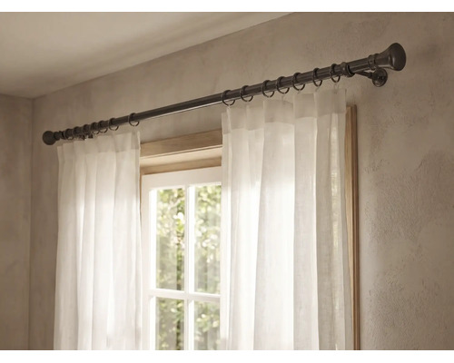 Vorhangstange aus Metall mit runden Endstücken und Vorhangringen, montiert über einem Fenster mit weißem Vorhang.