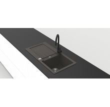 Moderne schwarze Einbauspüle aus Verbundwerkstoff mit Abtropffläche und hoher schwarzer Armatur in einer dunklen Arbeitsplatte.