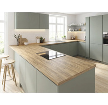 Moderne Einbauküche in Salbeigrün mit Arbeitsplatte in Holzoptik, Kochinsel inklusive Induktionskochfeld und weißen Wandfliesen.