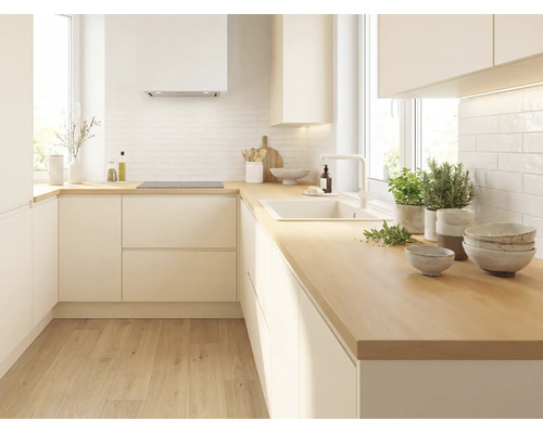 Moderne L-Küche mit hellen grifflosen Fronten, Arbeitsplatte aus Holz, weißem Fliesenspiegel, Spüle und Induktionskochfeld.