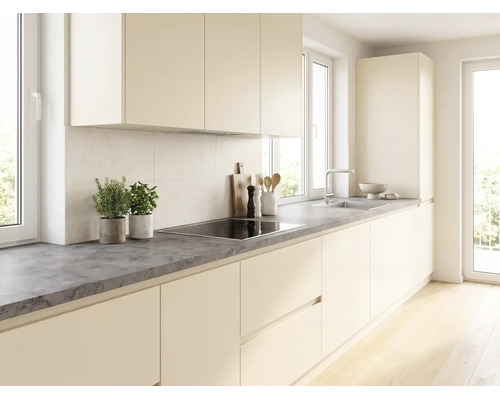 Moderne helle Küche mit grifflosen cremefarbenen Fronten, einer dunkelgrauen Arbeitsplatte in Steinoptik, Induktionskochfeld und Spüle.