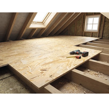 Dachbodenausbau mit OSB-Platten auf Holzbalkenlage, Akkuschrauber und Maßband auf der Arbeitsfläche im hellen Dachstock.