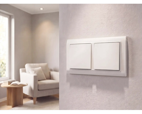 Moderner weißer Zweifach-Lichtschalter an einer strukturierten Wand in einem hellen Wohnzimmer mit Sessel und Beistelltisch.