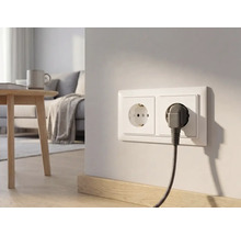 Doppelsteckdose an einer hellen Wand in einem modernen Wohnzimmer mit eingestecktem Stecker und stoffummanteltem Kabel.