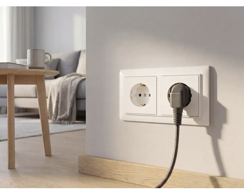 Doppelsteckdose an einer hellen Wand in einem modernen Wohnzimmer mit eingestecktem Stecker und stoffummanteltem Kabel.