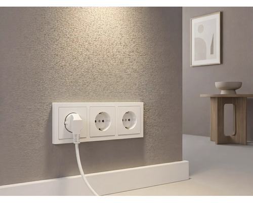Dreifach-Steckdose mit eingestecktem Stecker an einer strukturierten Wand in einem hellen Raum.