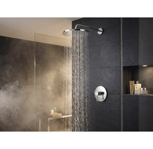 Wandmontierte Regendusche mit verchromter Oberfläche und runder Mischbatterie im modernen Badezimmer mit dunklen Fliesen und Glaswand.