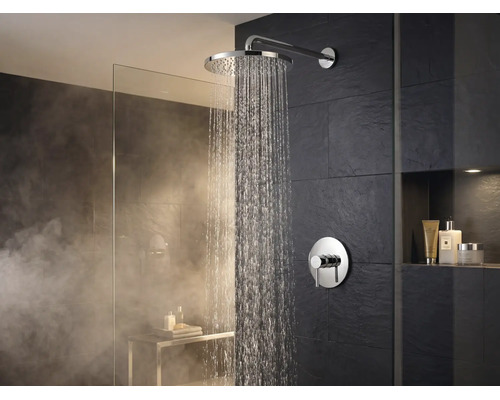 Wandmontierte Regendusche mit verchromter Oberfläche und runder Mischbatterie im modernen Badezimmer mit dunklen Fliesen und Glaswand.