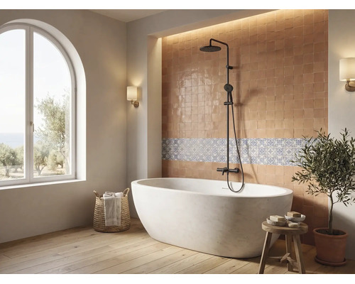 Helles Badezimmer mit freistehender Badewanne, schwarzem Duschsystem, Fliesenspiegel und großem Rundbogenfenster.