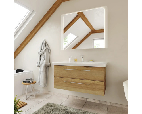 Modernes Badezimmer mit Waschtischunterschrank in Eichenoptik, weißem Waschbecken und beleuchtetem Spiegel unter einer Dachschräge mit Holzbalken.