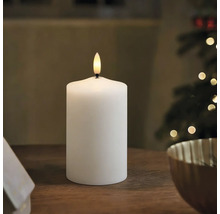 Weiße LED-Stumpenkerze auf einem Holztisch in einer weihnachtlich dekorierten Umgebung.