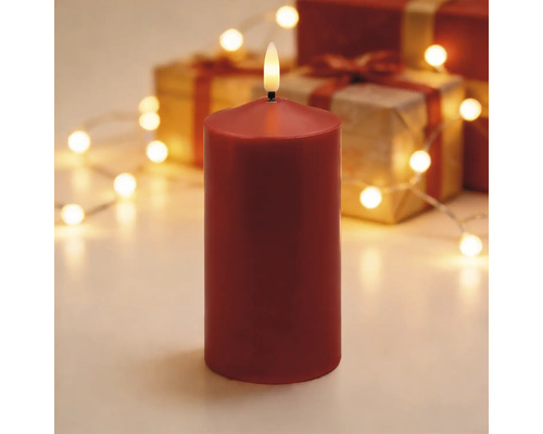 Rote LED-Stumpenkerze in einer festlichen Dekoration mit Geschenken und einer hellen Lichterkette.