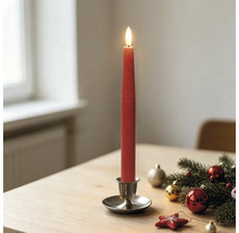 Rote LED-Stabkerze in einem Metallhalter auf einem Holztisch mit Weihnachtsdekoration aus Tannenzweigen und Christbaumkugeln.