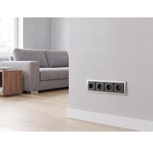 4-fach Steckdose installiert an einer Wand in einem hellen, modernen Wohnzimmer mit Sofa und Holzboden.