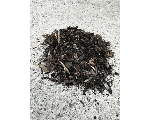 Dunkler Rindenmulch aus groben Holzstücken zur Bodenabdeckung im Garten.