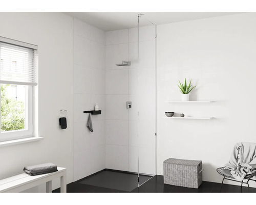 Modernes, helles Badezimmer mit begehbarer Dusche, Glastrennwand, weißen Fliesen, schwarzem Boden, Regalen und einem Wäschekorb aus Geflecht.