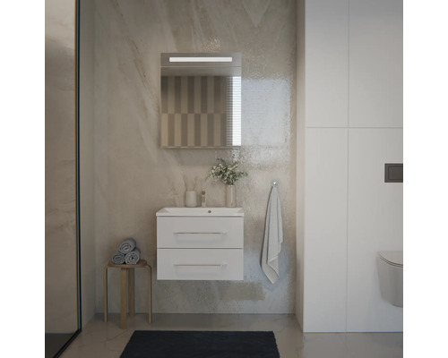 Modernes Badezimmer mit weißem Hängeschrank, zwei Schubladen, Waschbecken, LED-Spiegel und wandhängendem WC vor hellen Steinwänden.