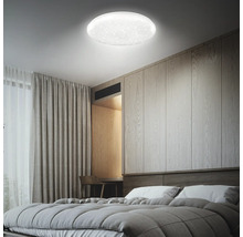 Moderne LED-Deckenleuchte mit Sternenhimmel-Effekt in einem hellen Schlafzimmer mit Holzwand und grauen Textilien.