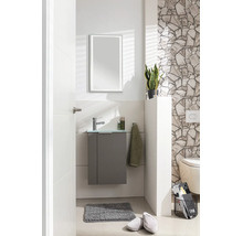 Modernes Gäste-WC mit grauem Unterschrank, Glaswaschbecken, Chromarmatur und LED-Spiegel vor einer hellen Wand mit Natursteinverblendern.