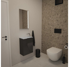 Modernes Gäste-WC mit wandhängendem WC, grauem Waschtischunterschrank mit kleinem Waschbecken, Spiegel und schwarzen Accessoires vor Steinwand.