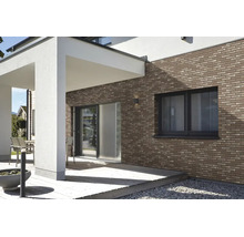 Moderne Hausfassade mit braunen Klinker-Riemchen an einer Terrasse mit Holzdeck und weißen Säulen.