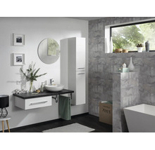 Modernes Badezimmer mit weißem Waschtischunterschrank, dunkler Arbeitsplatte, Aufsatzwaschbecken, hohem Seitenschrank und rundem Spiegel.