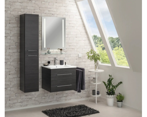 Modernes Badezimmer-Set in Holzoptik mit Waschtischunterschrank, Hochschrank und beleuchtetem Spiegel an einer Backsteinwand.