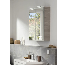Modernes Badezimmer mit zweitürigem Spiegelschrank inklusive LED-Beleuchtung und grauer Holzoptik, weißem Waschbecken und verchromter Armatur.
