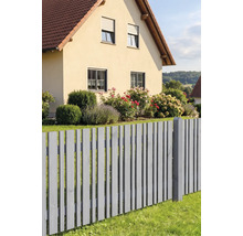 Grauer Lattenzaun aus Holz vor einem Wohnhaus mit Garten, der Rosen und Hortensien enthält.