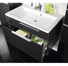 Waschtischunterschrank mit weißem Keramikwaschbecken und verchromter Armatur, eine geöffnete Schublade mit Badutensilien.