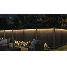 Beleuchteter Sichtschutzzaun im Garten bei Nacht mit LED-Lichtleiste, Gartenmöbeln und Pflanzen.