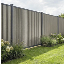Sichtschutzzaun aus vertikalen Lamellen mit Metallpfosten in einem Garten mit Pflanzen und Rasen.