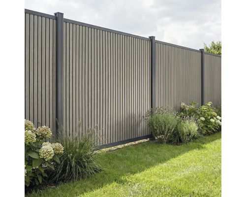 Sichtschutzzaun aus vertikalen Lamellen mit Metallpfosten in einem Garten mit Pflanzen und Rasen.
