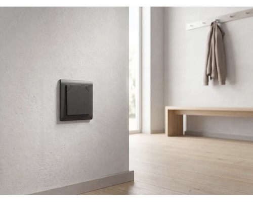 Dunkelgrauer moderner Lichtschalter an einer hellen Wand in einem minimalistisch eingerichteten, hellen Flur mit Holzboden.
