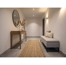 Heller Flur mit Holz-Konsolentisch, rundem Spiegel, Juteläufer und gepolsterter Sitzbank. Modernes, minimalistisches Design mit warmer Beleuchtung.