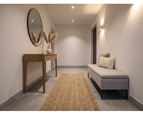 Heller Flur mit Holz-Konsolentisch, rundem Spiegel, Juteläufer und gepolsterter Sitzbank. Modernes, minimalistisches Design mit warmer Beleuchtung.