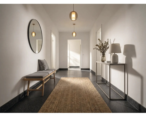 Hell gestalteter Flur mit Holzbank, rundem Wandspiegel, Juteläufer, Konsolentisch mit Tischlampe und zwei Pendelleuchten.