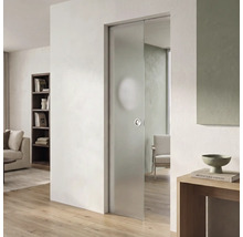Moderne Glasschiebetür aus mattiertem Glas in einem hellen Wohnraum mit hellem Parkettboden und weißer Wand.