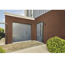 Außenfassade eines Hauses mit Klinkerriemchen, grauem Garagentor, moderner Haustür und gepflastertem Eingangsbereich.