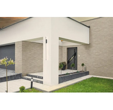 Moderne schwarze Außenwandleuchte an einem weißen Pfeiler, Hauseingang mit Klinkerfassade, Garage und Gartenbereich.