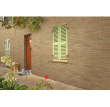 Fassade mit Klinkerriemchen in Ziegeloptik, Fensterläden und einer hölzernen Eingangstür im Außenbereich.