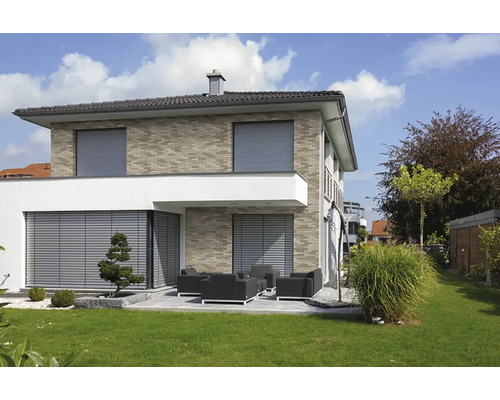 Modernes Wohnhaus mit Außenjalousien und Rollläden an den Fenstern sowie einer Terrasse mit Gartenmöbeln und gepflegtem Rasen.