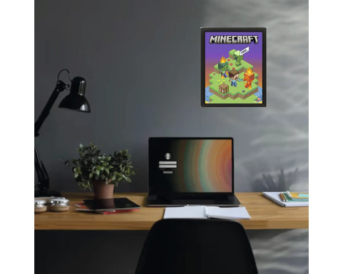 Minecraft Poster in einem schwarzen Rahmen an einer dunklen Wand über einem Schreibtisch mit Laptop und Pflanze.