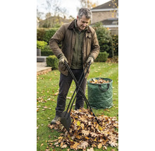 Ein Mann nutzt einen Laubgreifer mit langen Stielen, um Herbstlaub auf einer Rasenfläche in einen Gartenabfallsack zu sammeln.