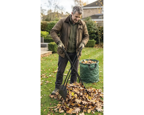 Ein Mann nutzt einen Laubgreifer mit langen Stielen, um Herbstlaub auf einer Rasenfläche in einen Gartenabfallsack zu sammeln.