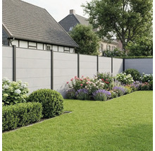 Moderner Sichtschutzzaun in Betonoptik mit dunklen Metallpfosten in einem Garten mit Blumenbeeten und Rasenfläche.