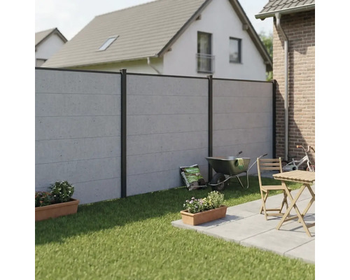 Moderner Sichtschutzzaun in Betonoptik mit dunklen Aluminiumpfosten im Garten, neben einer Terrasse mit Holzmöbeln und Rasenfläche.
