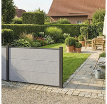 Moderner Sichtschutzzaun in Betonoptik im Garten mit Rasen, Beeten und einer gepflasterten Terrasse mit Holzmöbeln.