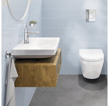 Modernes, helles Badezimmer mit Keramik-Waschbecken auf Holz-Unterschrank, verchromter Armatur und Wand-WC vor gefliesten Wänden.